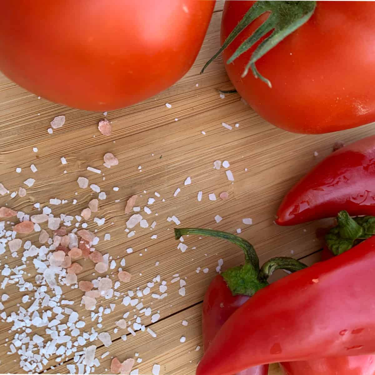 Tomatoes, chilis, salt on a board.