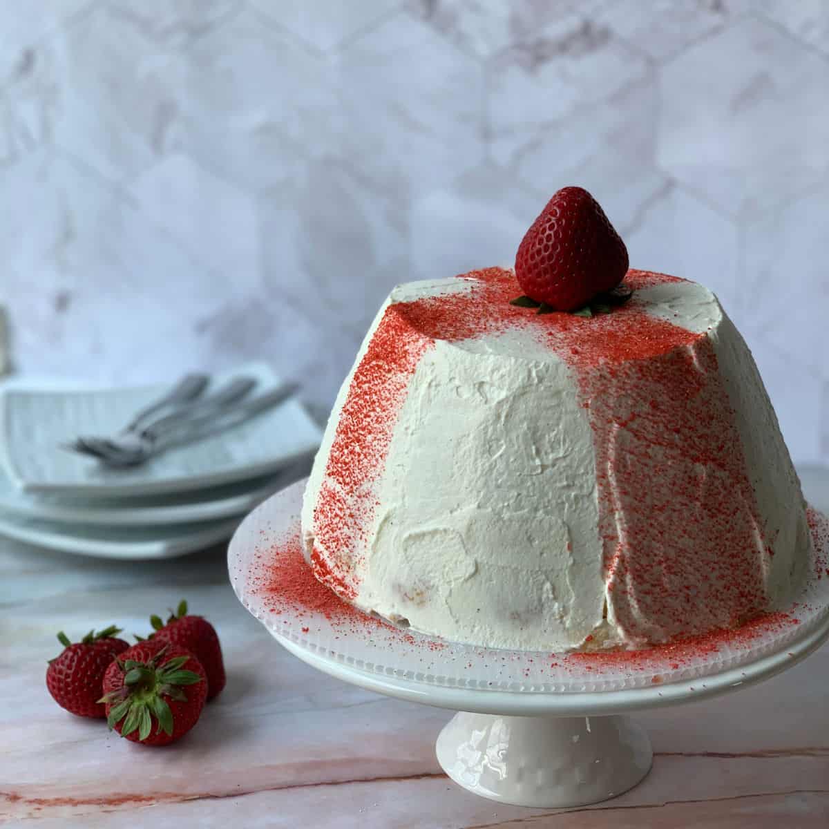 Strawberry Zuccotto Fiorentino in a fore ground, three strawberries and plates in the background.