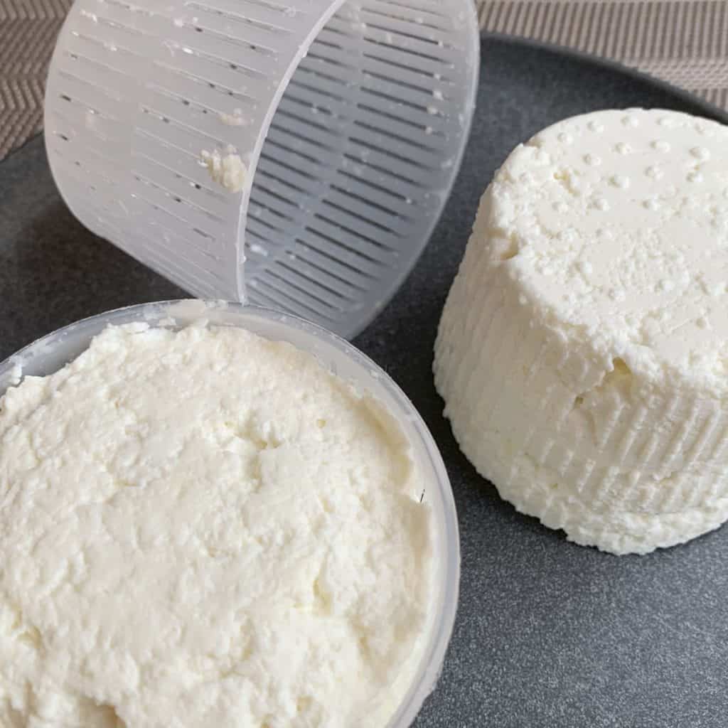 Home made ricotta cheese out of the basket on a plate.