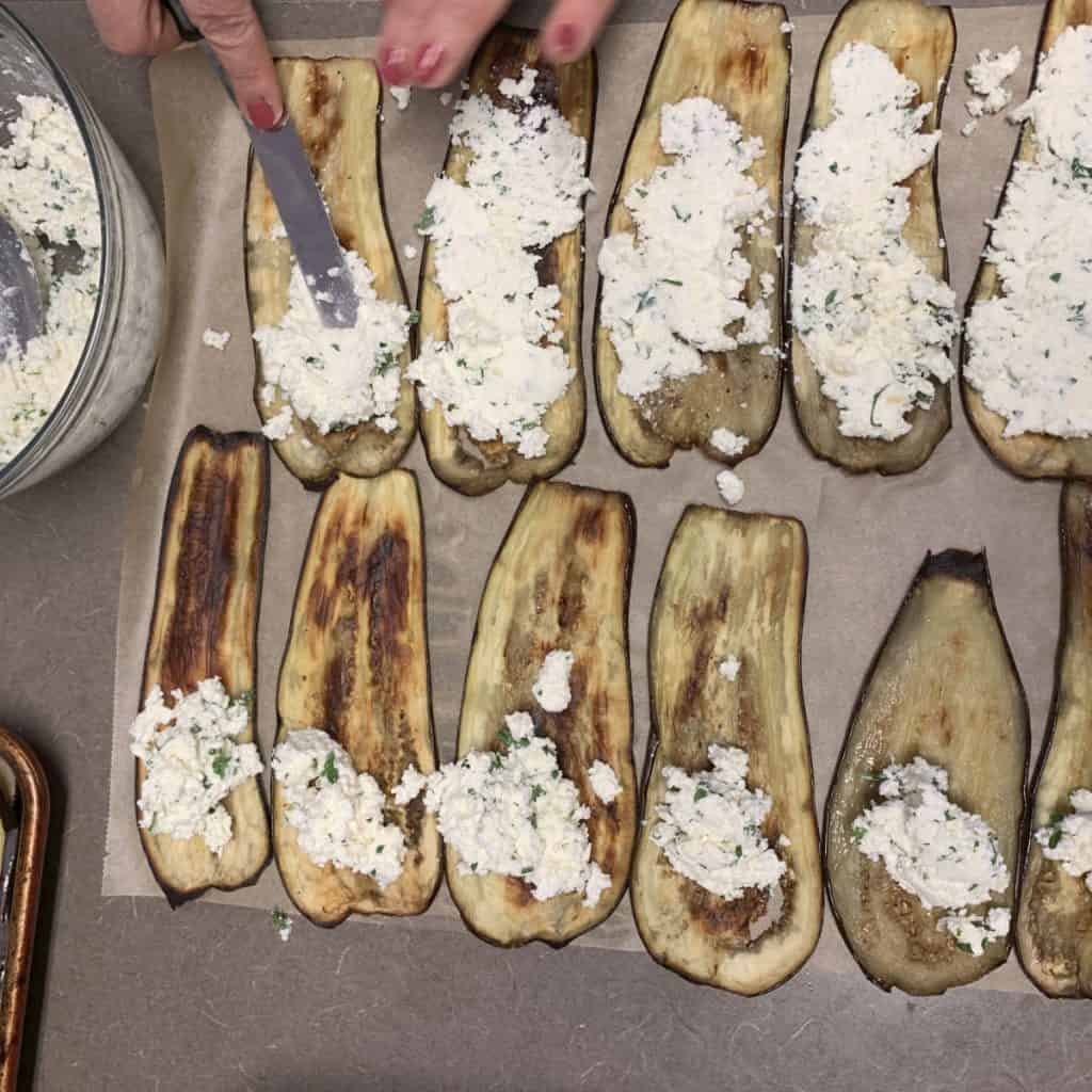 Spreading the cheese blend on roasted eggplants.