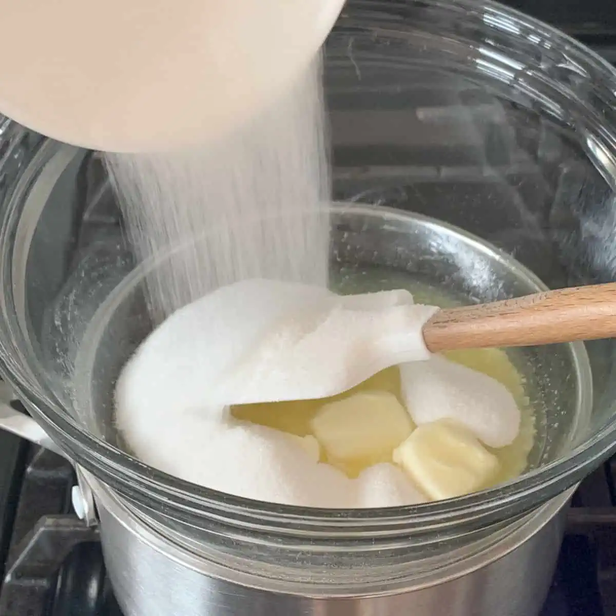 Adding sugar to a butter in double boiler.