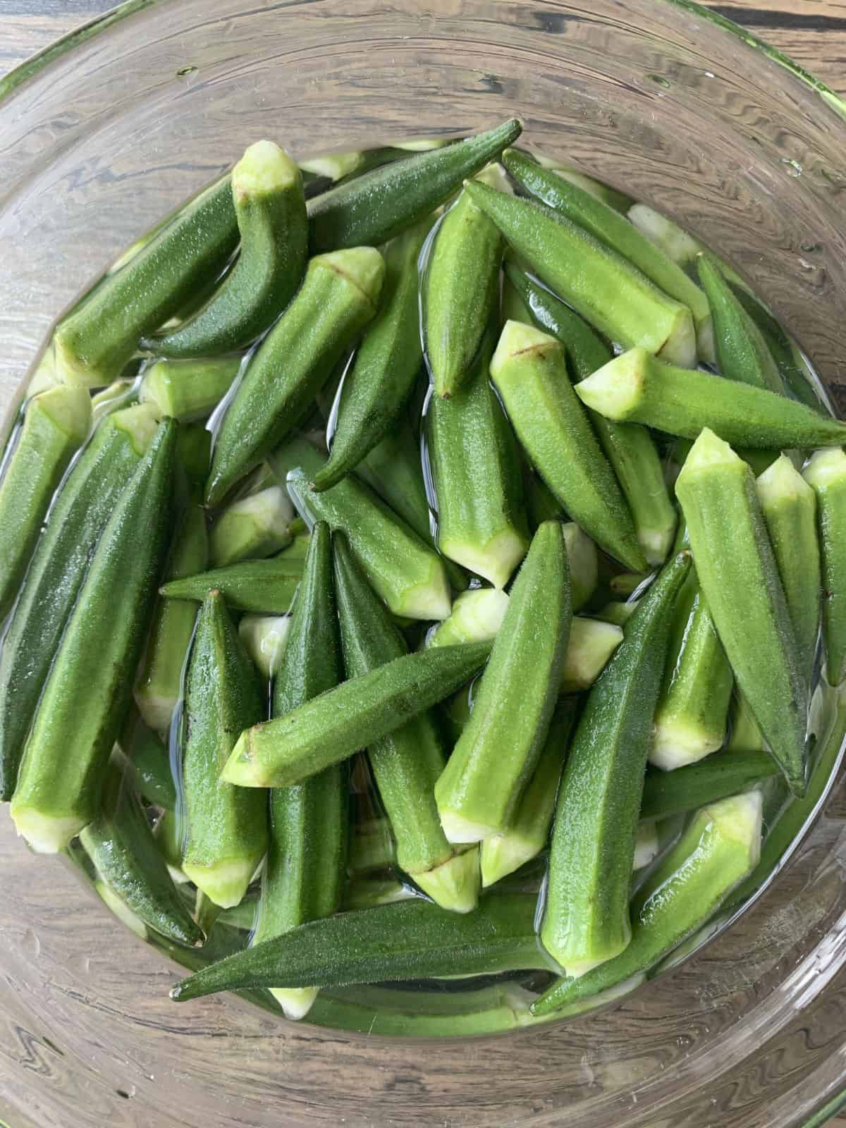 Trimmed okra in a water lemon bath.