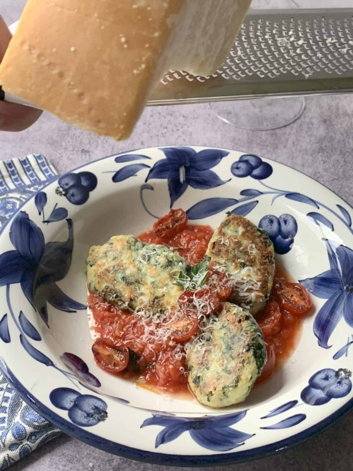 Grating cheese on ricotta kale gnocchi.