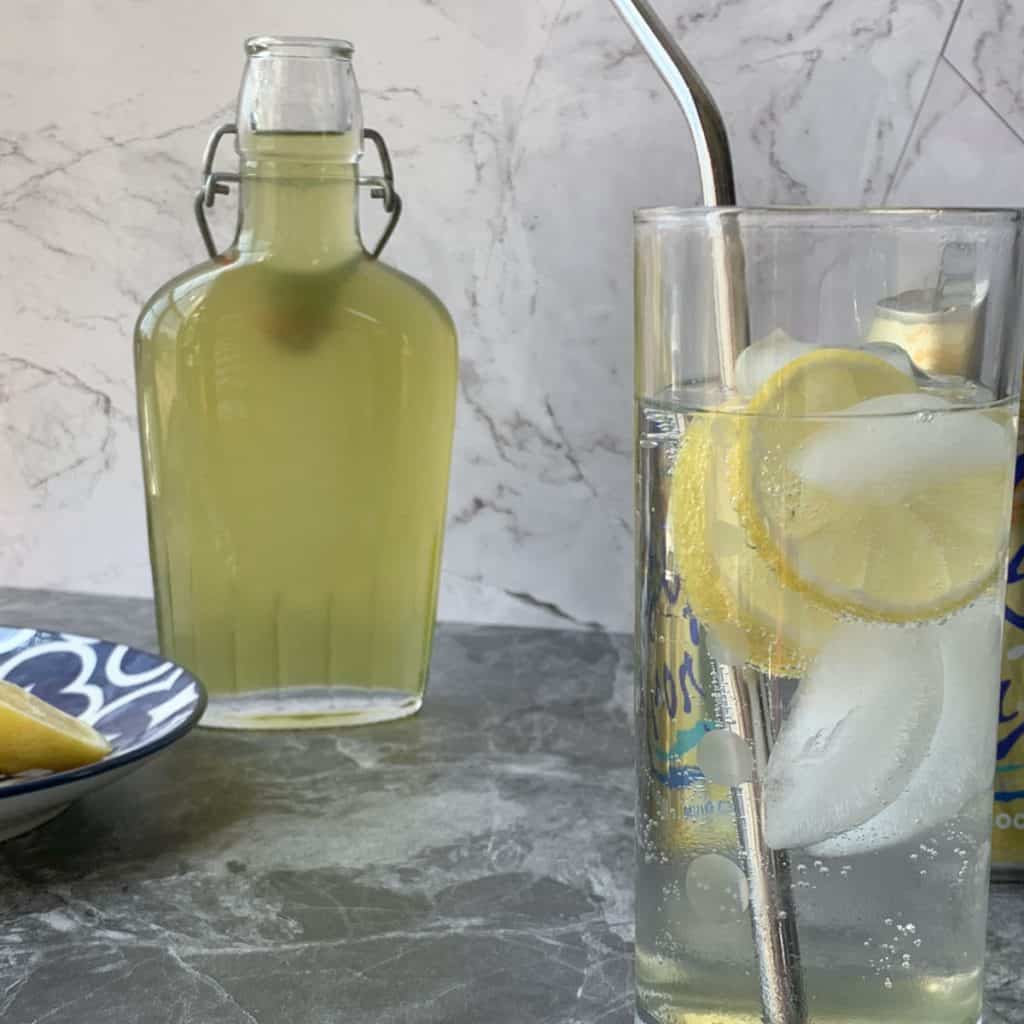 Glass of cooling tarragon syrup with lemon slices.
