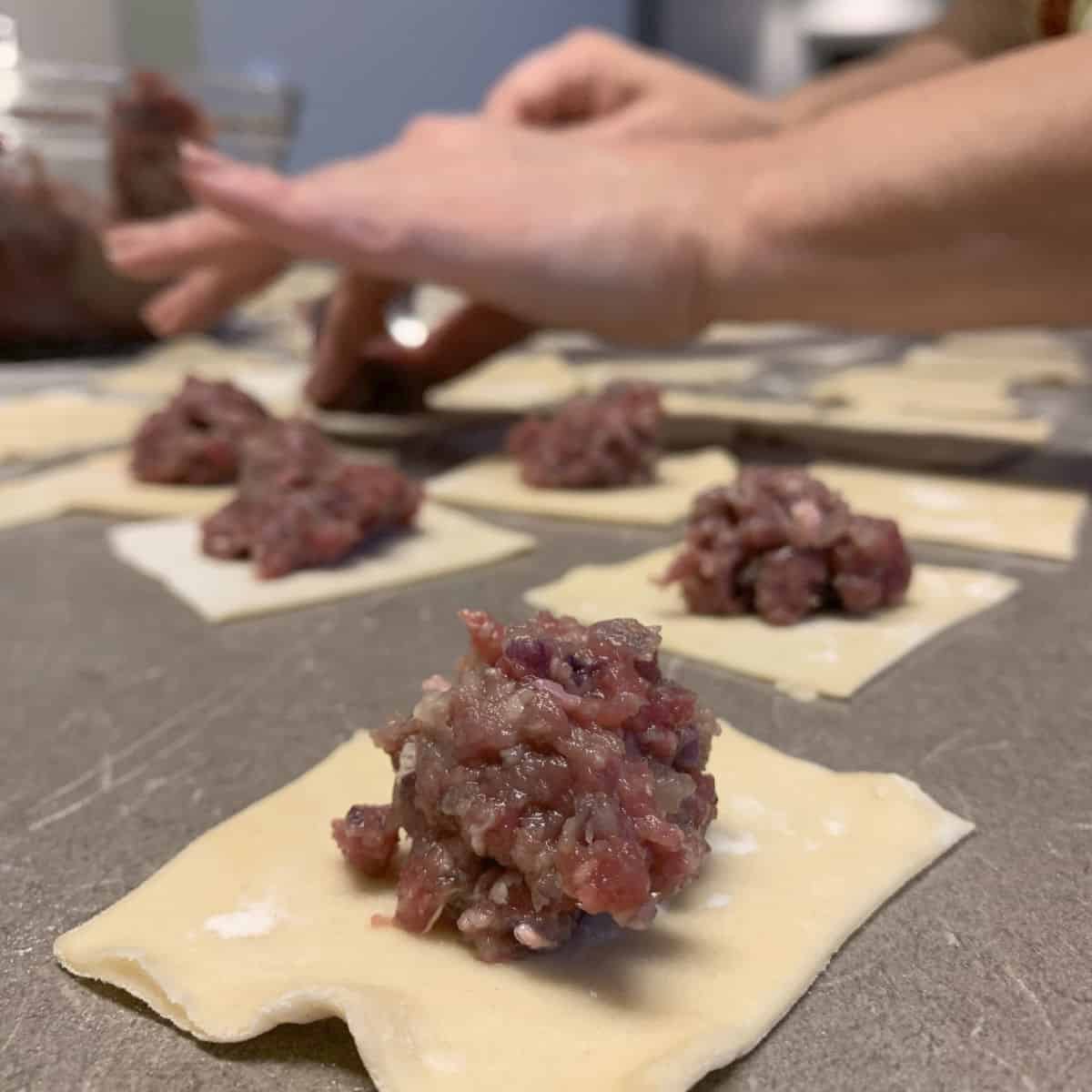 Close up shot of a square dough with a meat filling.