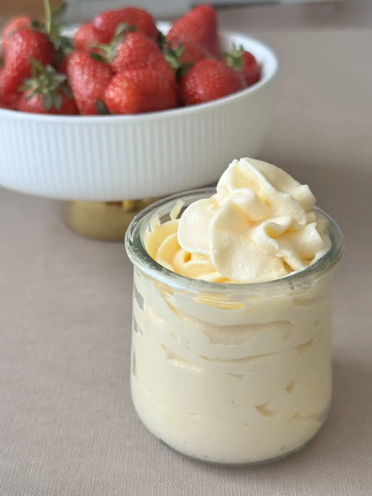 A Mousseline Cream in a jar and a bowl of strawberries.