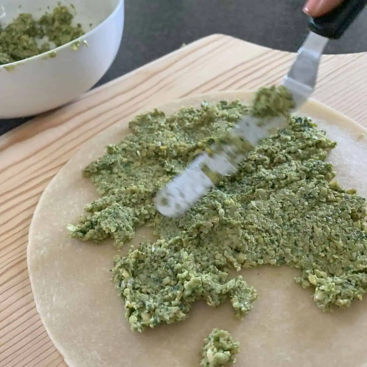 Spreading falafel mixture on a tortilla.