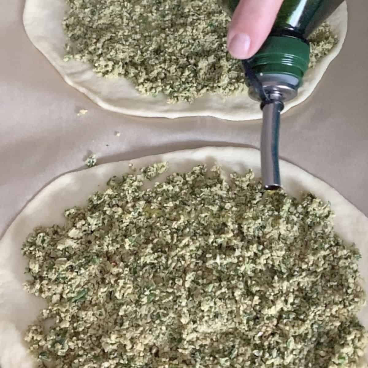 Drizzling oil on a falafel pizza.