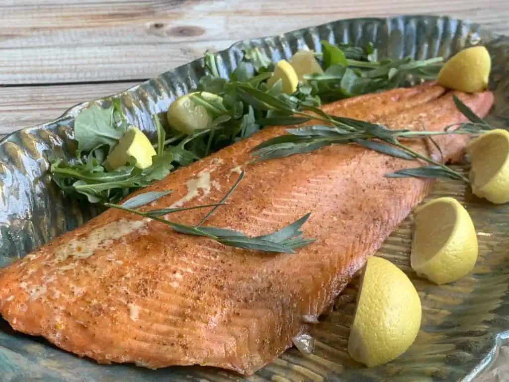 Smoked salmon on a green platter with lemons and tarragon.