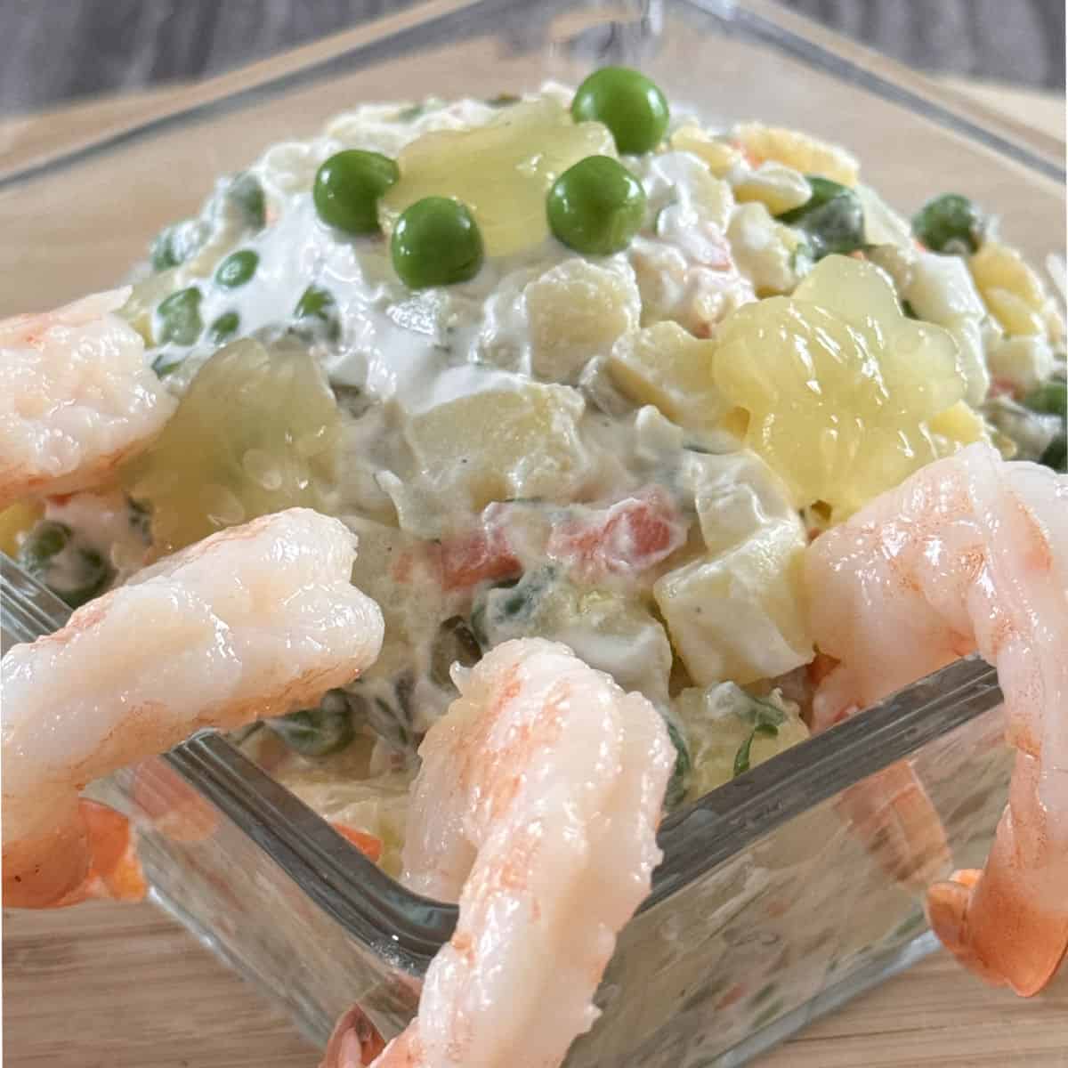 Olivier salad in a glass bowl with shrimp.