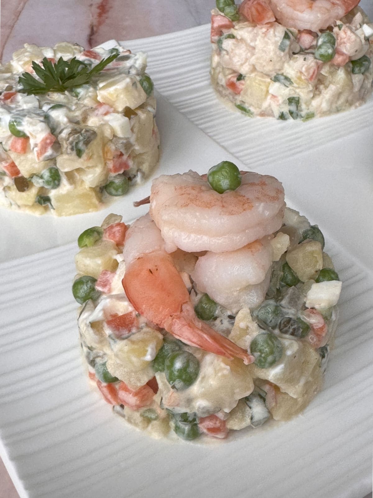 A plate of olivier salad with shrimp and vegetables.