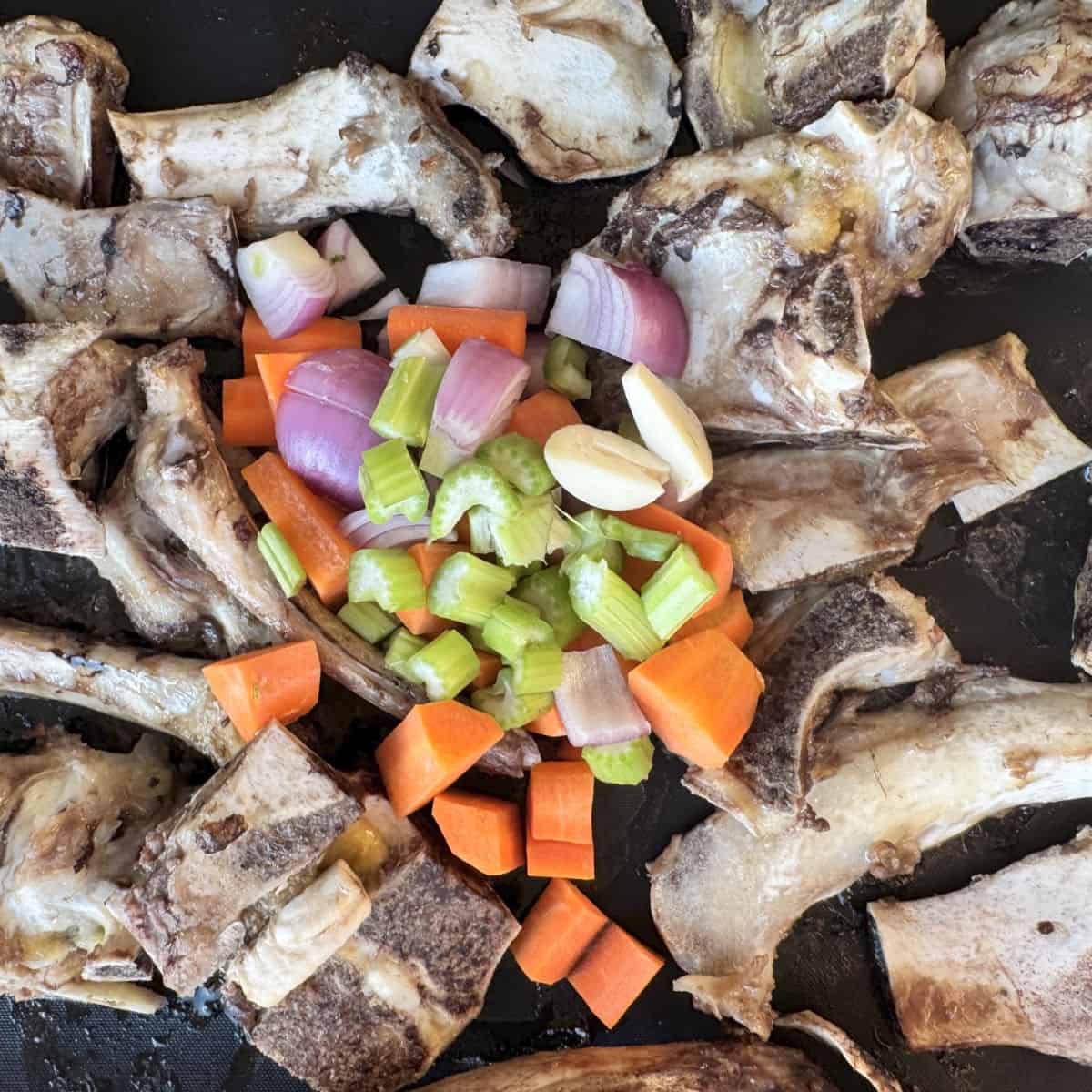 Adding vegetables to the roasting pan.