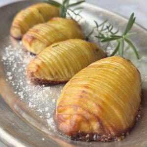Hasselback potatoes on a silver plate.