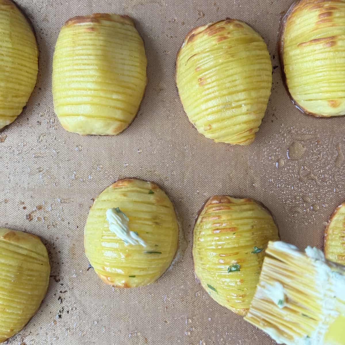 Brushing butter and rosemary on the potatoes.