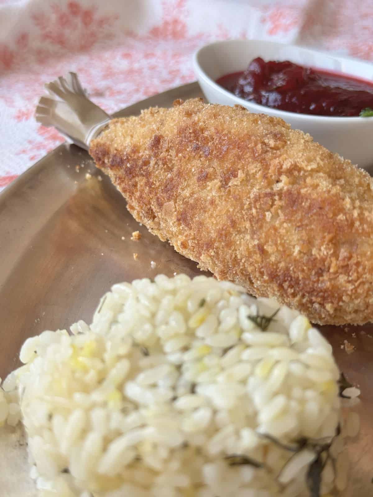 Chicken Kiev kotlet with a bed of rice and cranberry sauce.