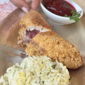 Chicken Kiev kotlet cross-cut with a bed of rice and cranberry sauce.