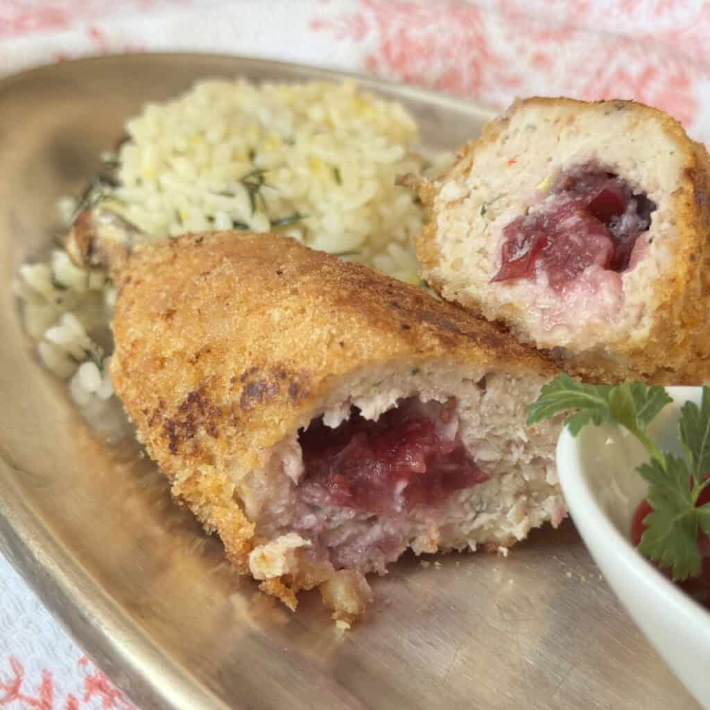 Chicken Kiev kotlet cross-cut with a bed of rice and cranberry sauce.