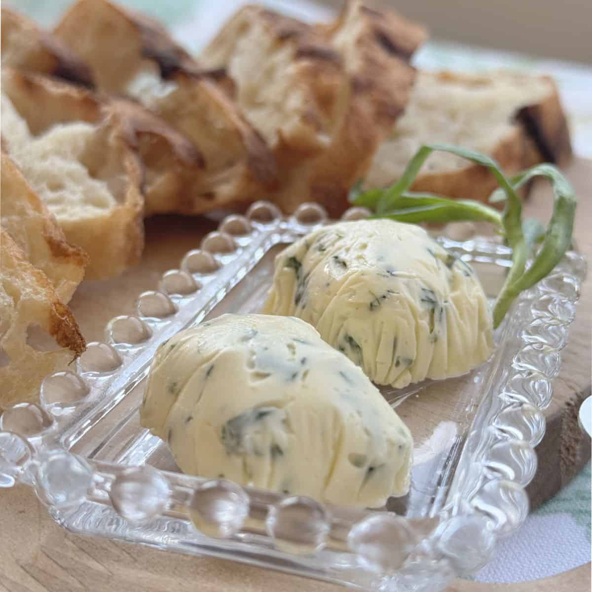 Tarragon compound butter sliced on a board with crusty bread.