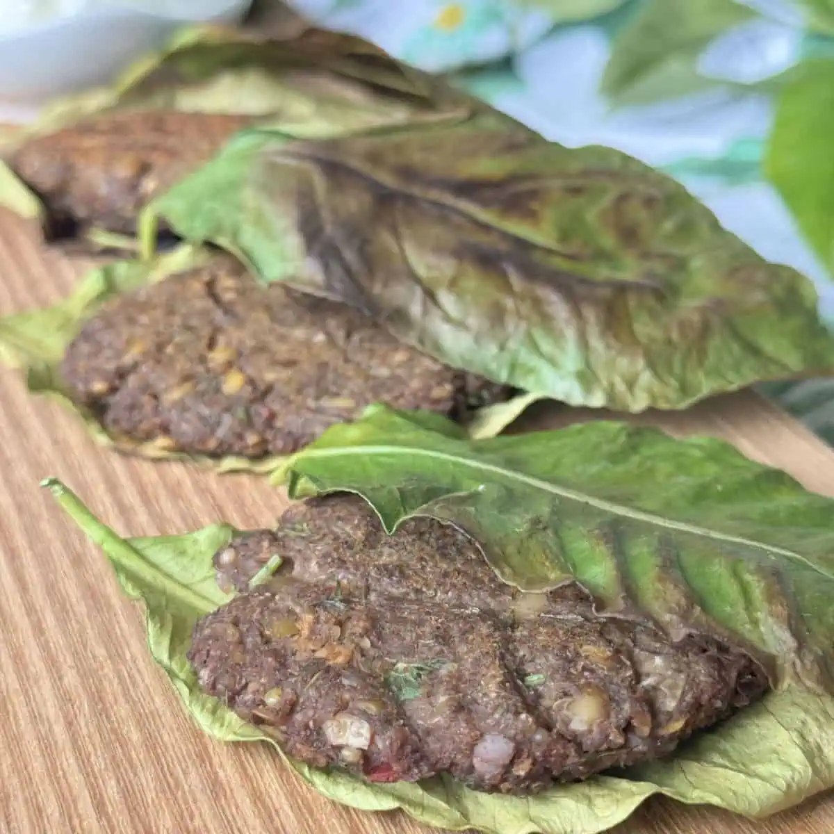 Lentil patties in lemon leaves on a wooden board.