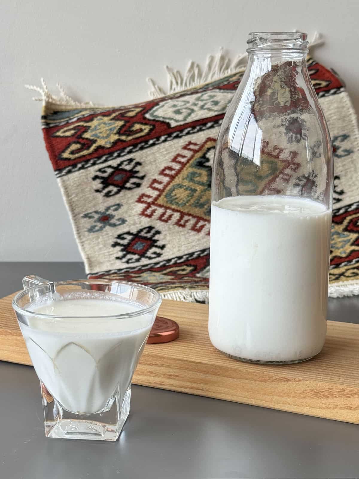 Bottle of homemade kefir and full glass against the Armenian carpet.