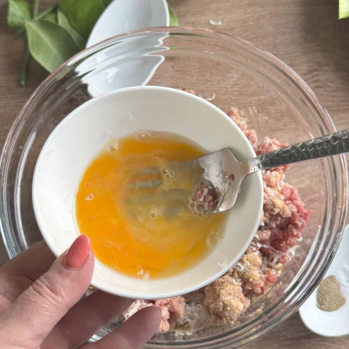 Adding the beaten egg to the meat mixture.