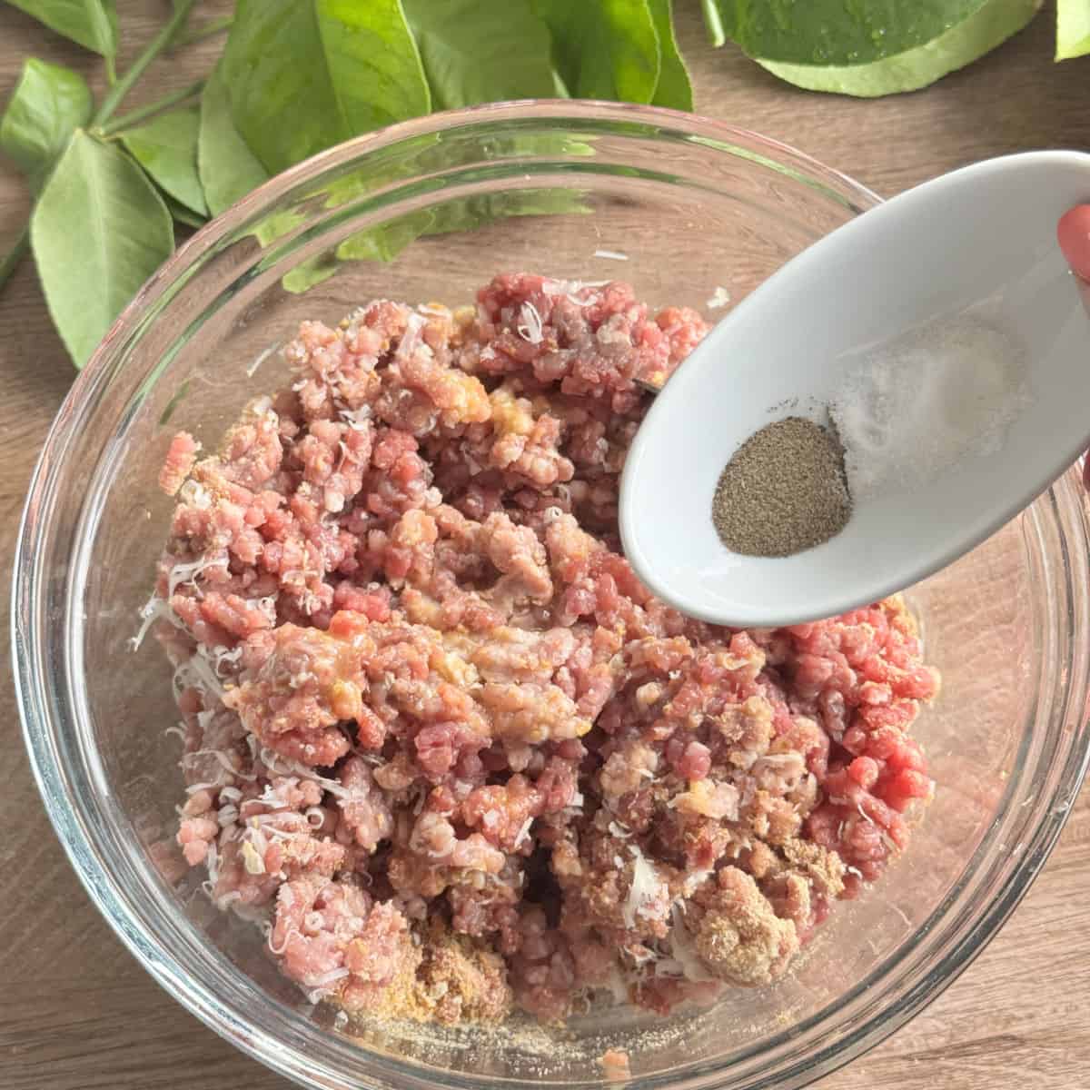 Adding seasoning to the meat mixture.