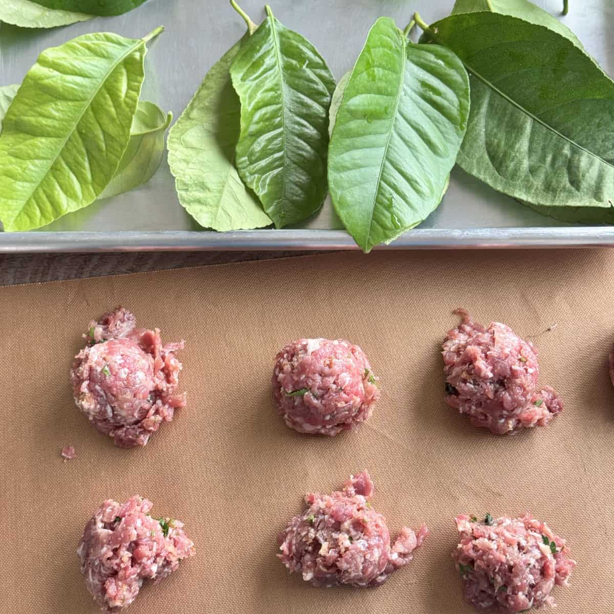 Shaping meatballs and laying down the lemon leaves.