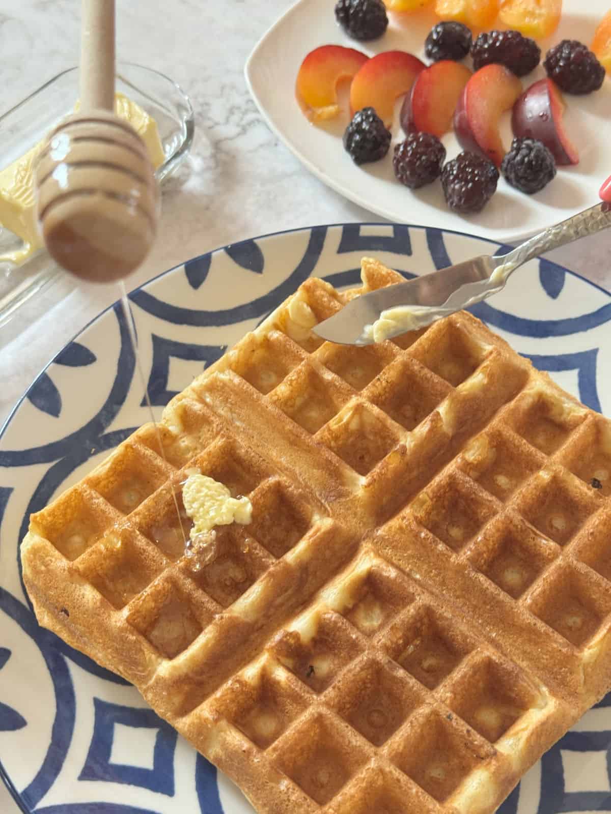 Close-up shot of a kefir waffle with berries and honey.