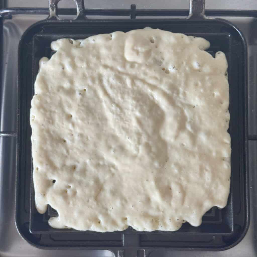 Cooking waffle in a waffle iron.