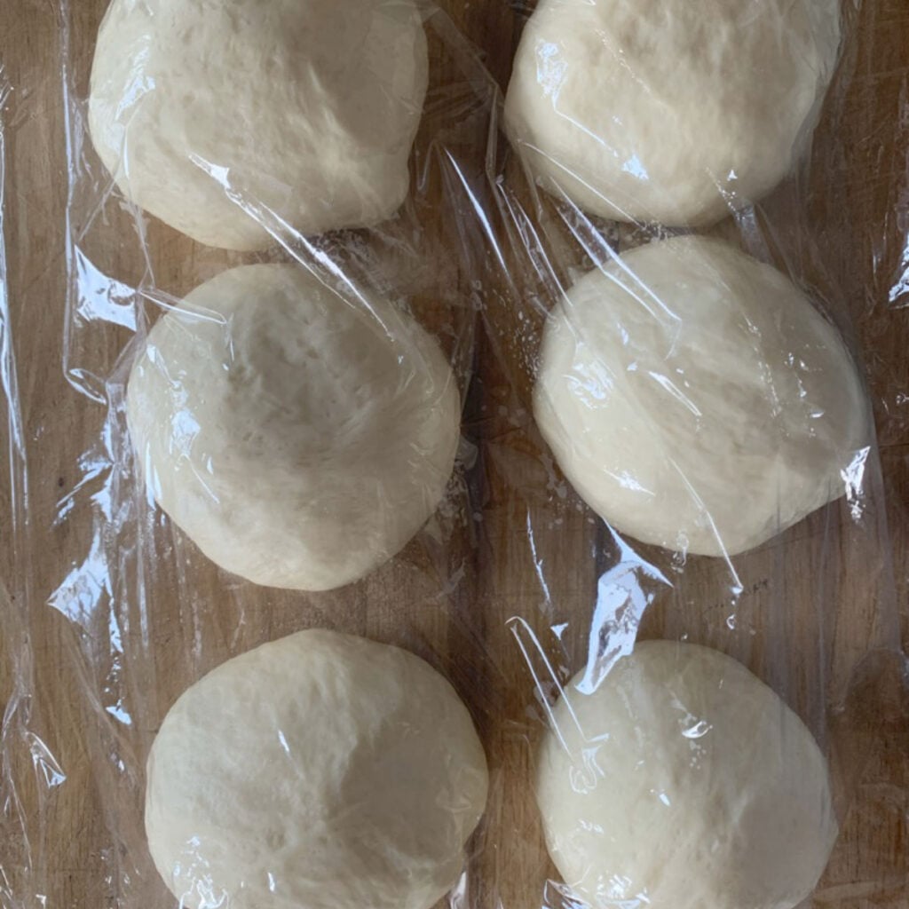 Smooth, elastic un-yeasted dough divided into 6 balls.