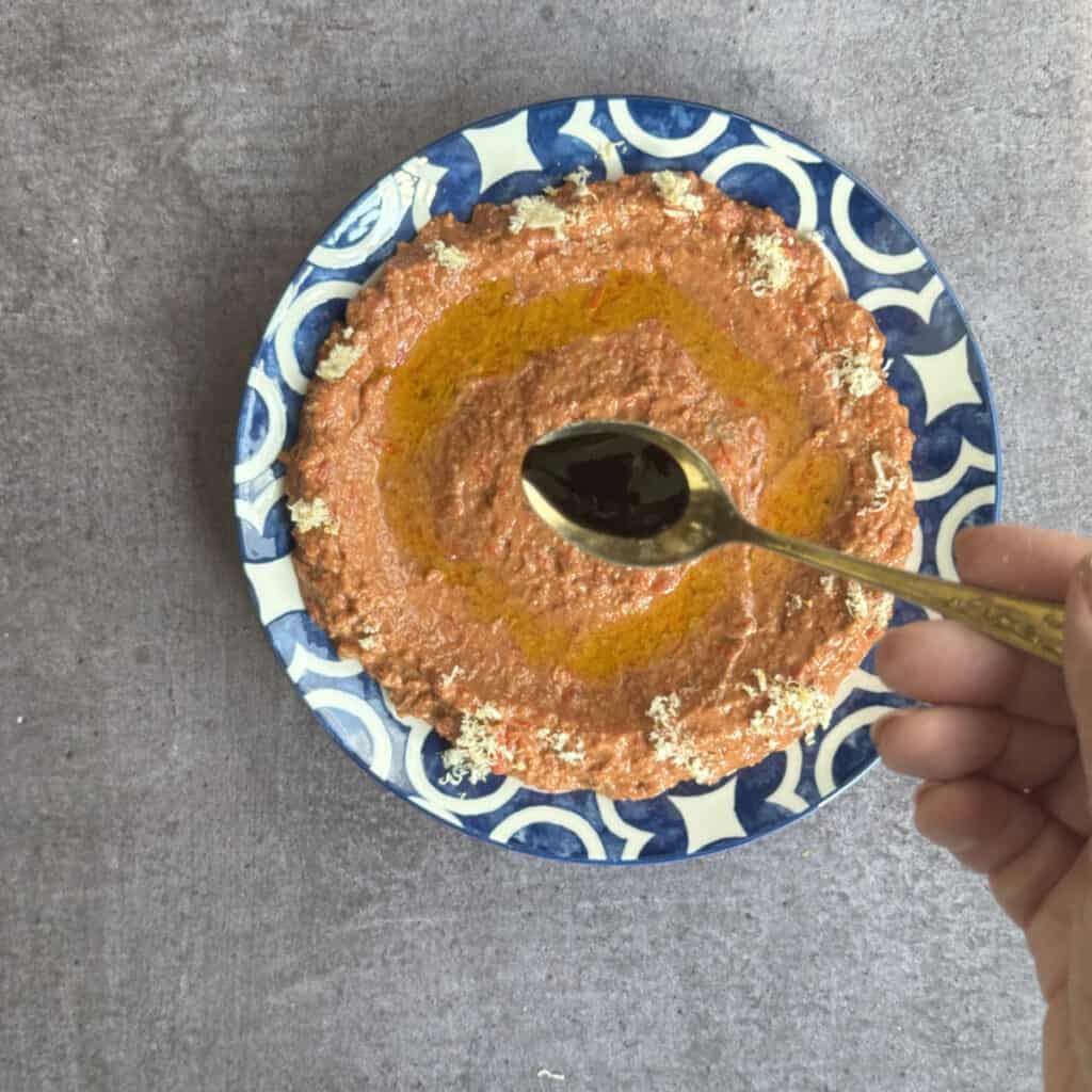 Drizzling pomegranate molasses on the ready dip.