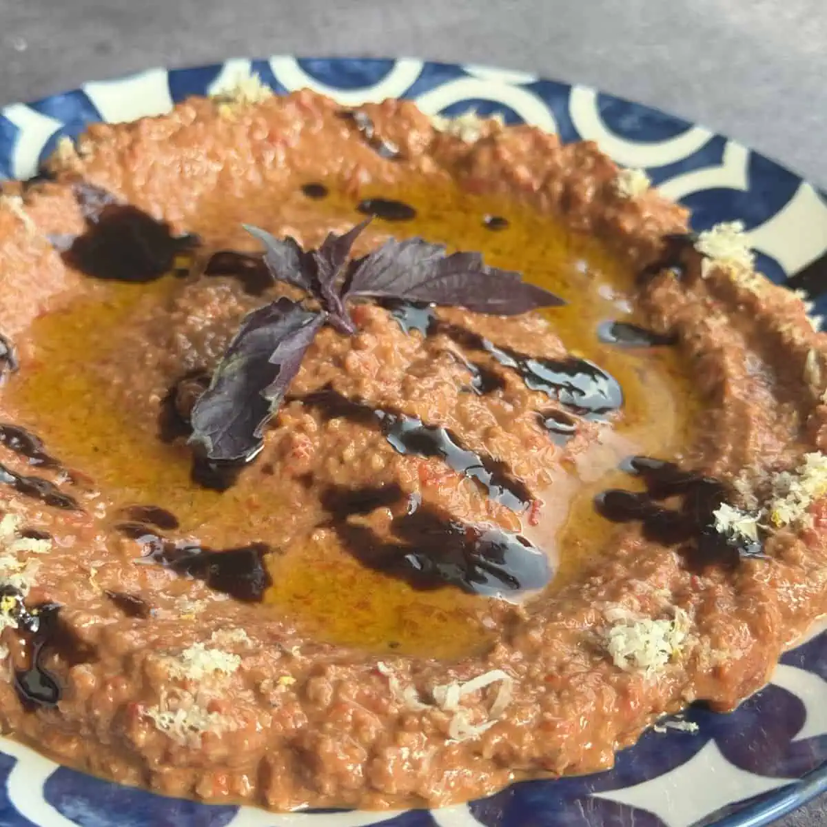 Muhammara in a plate drizzled with pomegranate molasses.