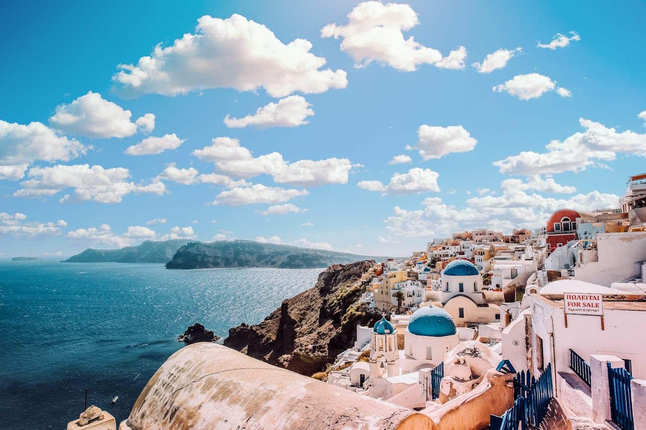 about-03 Captivating view of Santorini's famous blue-domed buildings under a vibrant sky.