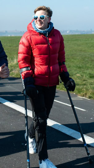 A person in a red coat and ski gear walking on a road AI-generated content may be incorrect.