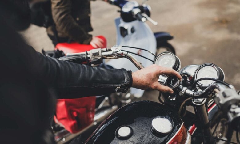 Motorcycle with rider adjusting the speedometer in an outdoor setting, adventure biking, outdoor exploration, motorbike gear.