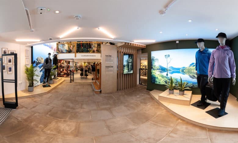 Outdoor clothing retail store display featuring mannequins, outdoor gear, and scenic rainforest mural interior.