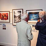 Impression of two elderly men viewing outdoor photography at an exhibition, showcasing adventure and nature photography.