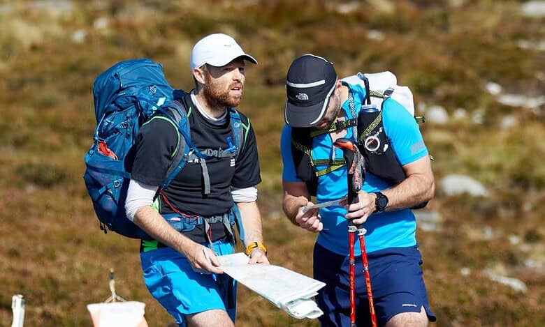 1. Two male hikers checking a map during outdoor trekking adventure with backpacks and hiking gear.