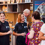Enjoying outdoor adventure talk at an indoor event, featuring smiling attendees with outdoor gear and branded clothing.