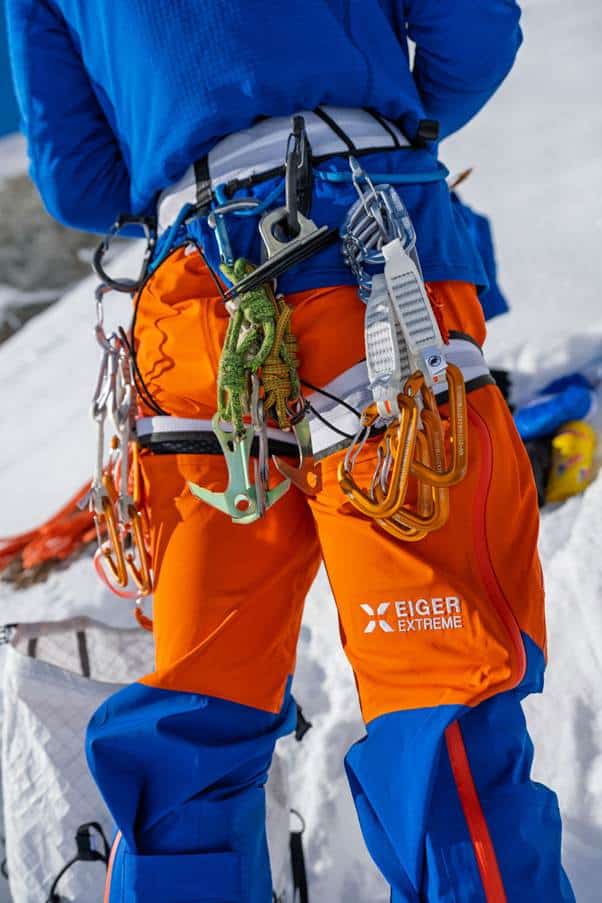 Climber with safety gear and carabiners in snowy outdoor mountain setting.