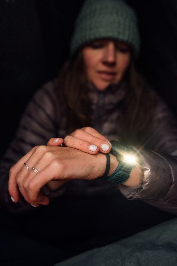 Women wearing outdoor gear using a headlamp for camping or hiking.