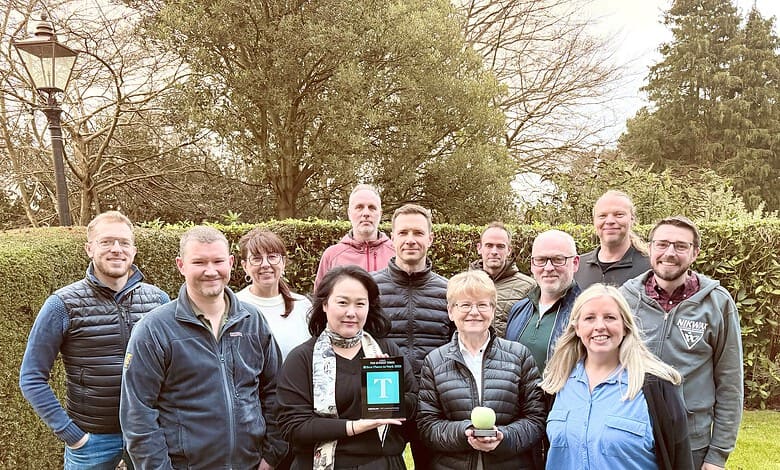 Group of people outdoors holding awards and a tennis ball.