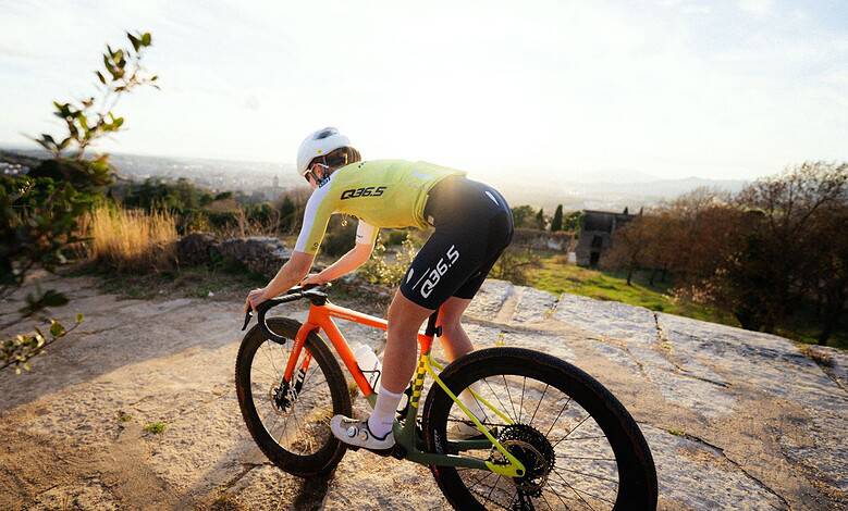 Cyclist riding a mountain bike on rocky terrain with scenic views in the background.
