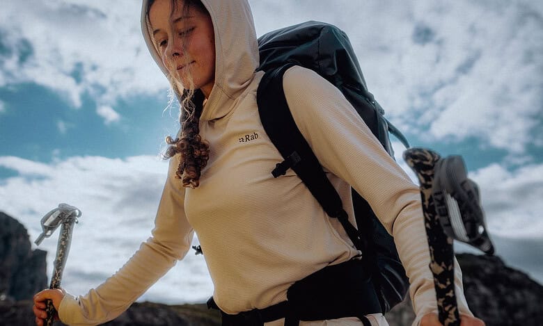 Hiker girl with backpack and trekking poles enjoying outdoor adventure.
