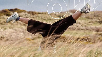 Person doing a handstand in a grassy field during daytime, embracing outdoor adventure.