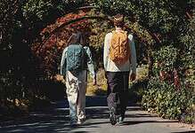 Hikers walking through a lush, green archway on a trail in autumn.