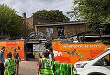 Outdoor mural on a building with people and cars in front, promoting outdoor activities.
