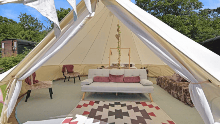 Interior view of a luxury glamping tent with seating and decor.