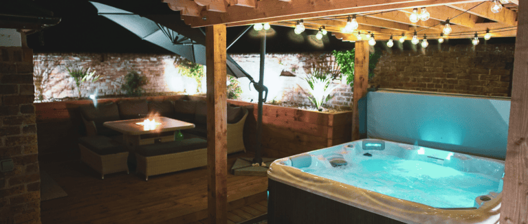 Outdoor hot tub under a wooden pergola at Cheeseman's Farm Stables.