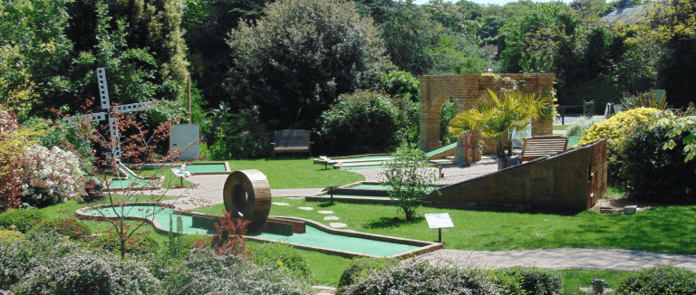 Miniature golf course with lush greenery and decorative structures at Quex Adventure Golf.